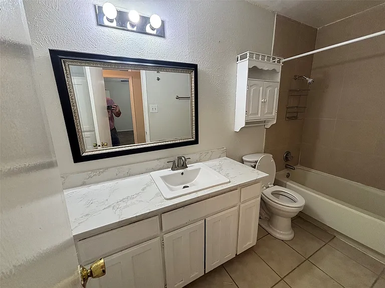 Bathroom featuring a vanity with an integrated sink, a large framed mirror, and a three-light fixture