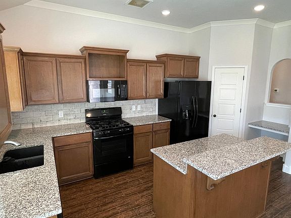 Kitchen with large newer side-by-side fridge, dishwasher, oven/stove, new microwave, and center island with bar top. Abundant storage, corner pantry, and built-in desk area in kitchen.
