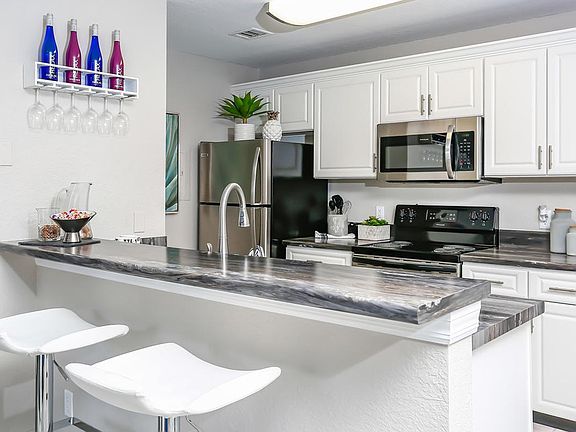 Updated kitchens featuring black fusion counter tops, stainless steel appliances, goose neck faucet, and a breakfast bar.