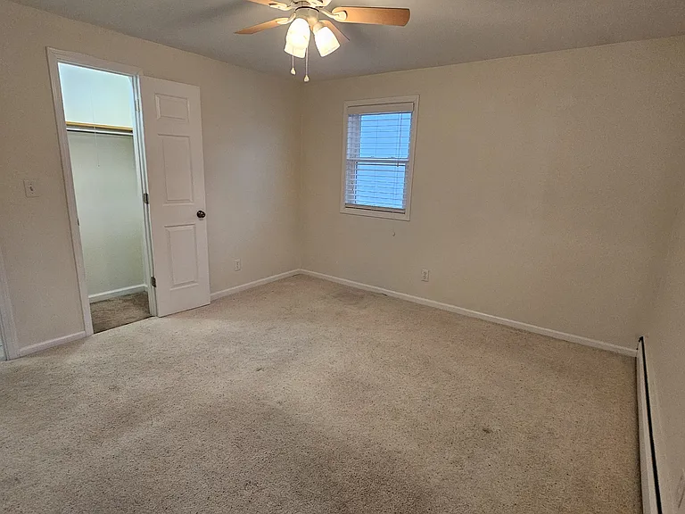 Master bedroom with ceiling fan and spacious closet