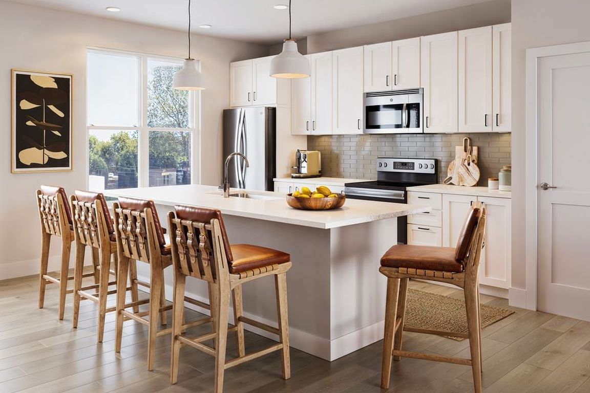 Townhome kitchen with white cabinetry, tile backsplash, stainless steel appliances, pendant lighting, and hard-surface vinyl plank flooring (Rendering)