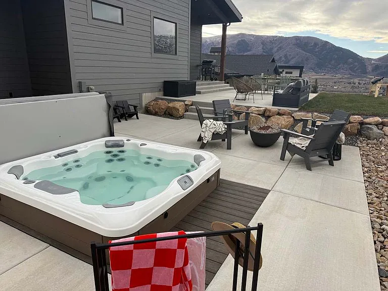 Private hot tub next to piped natural gas fire pit and chairs.