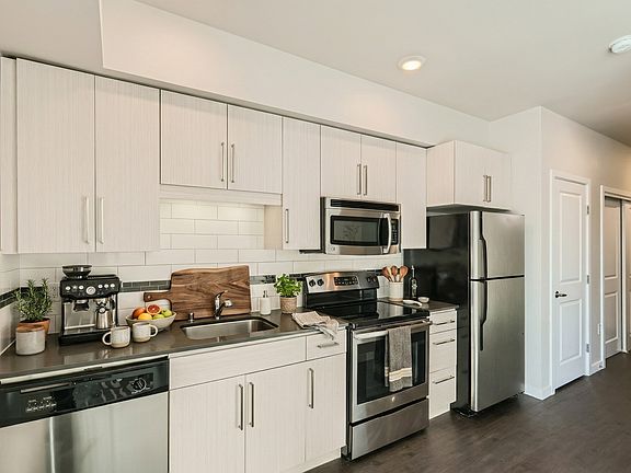 Kitchen at 306 Queen Anne featuring stainless steel appliances, dark countertops, subway tile, and flat-panel cabinets.