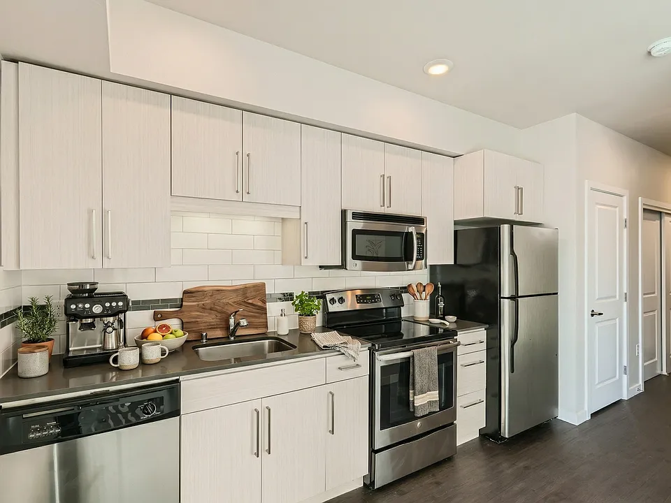 Kitchen at 306 Queen Anne featuring stainless steel appliances, dark countertops, subway tile, and flat-panel cabinets.