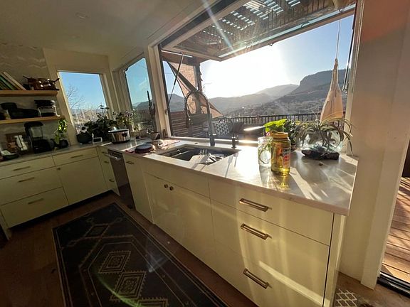 Large kitchen awning pass through window lifts completely up and out to let the outdoors in and frames the view of Longs Peak beautifully.
