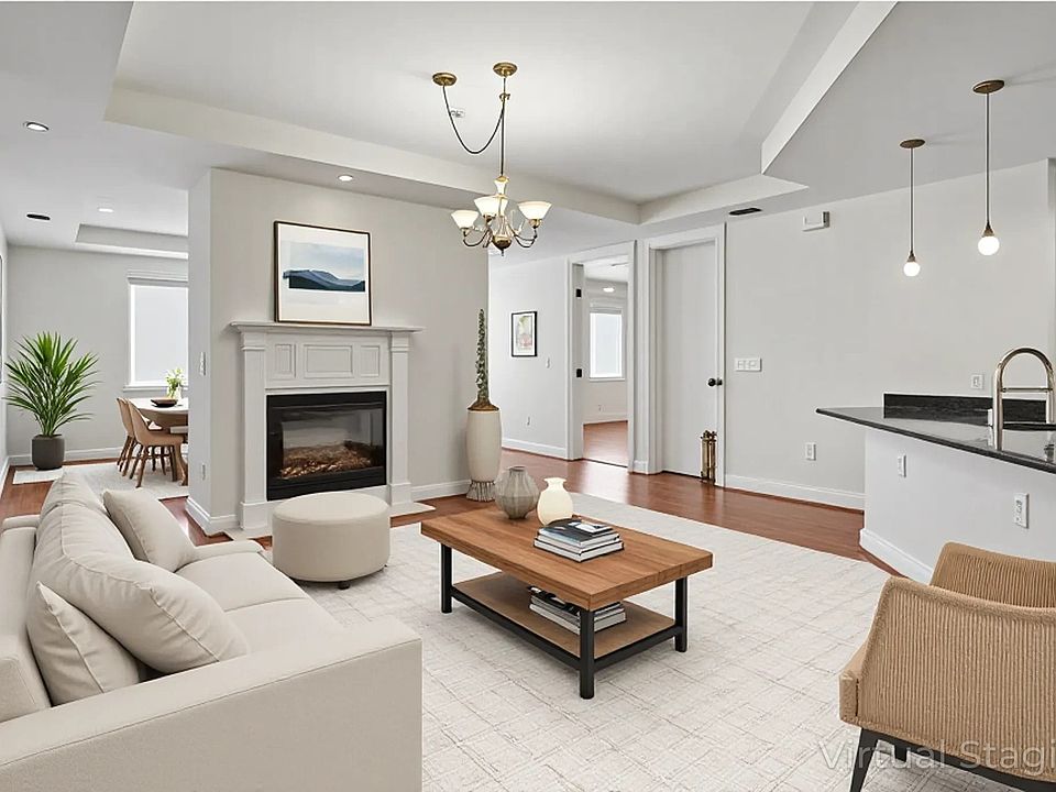 Living room featuring recessed lighting, a glass covered fireplace, a tray ceiling, wood finished floors, and a chandelier