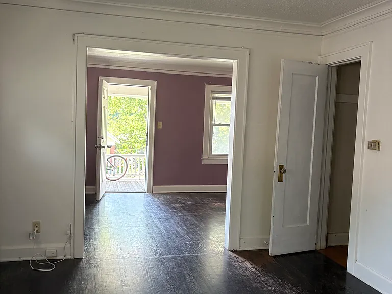 Looking from the corner of the dining room into the living room. Open door in dining room is to coat closet. Other door opens to the porch.