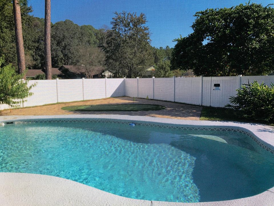Large swimming pool with putting green. Enclosed patio with dining table, and lounging chairs overlooking pool.