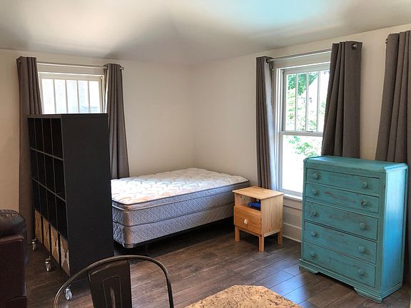 Sleeping area separated from rest of living area by tall bookcase. Bed, nightstand, and dresser can remain if desired.