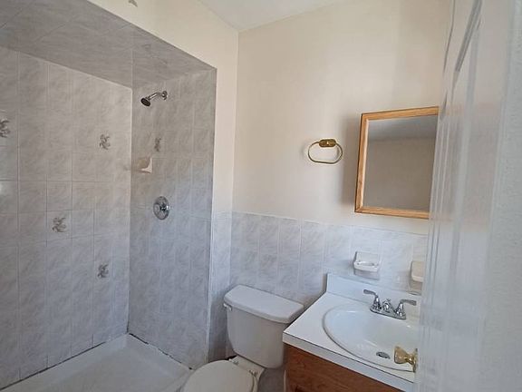 Clean and well-kept bathroom featuring a walk-in shower with tiled walls, modern fixtures, and a vanity with storage below. Neutral tones give the space a bright, fresh feel, making it easy to maintain and comfortable for daily use.