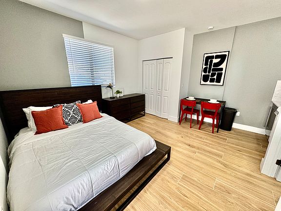 Furnished bedroom featuring a full bed, dresser, and a compact dining/work table, plus a closet and window blinds.