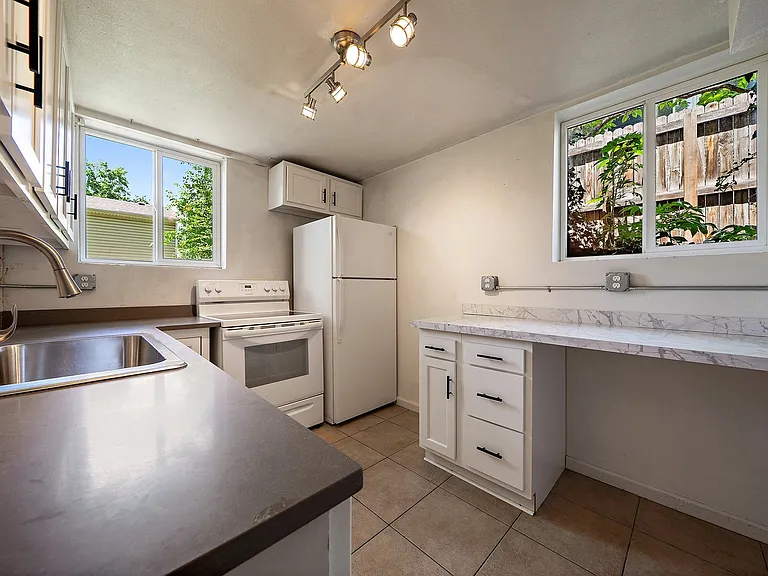 Updated kitchen with newer cabinets and quartz countertops. Window to backyard. Extra drawer storage and eating space or desk or extra counter space to the right. Large pantry where photographer is standing in front of
