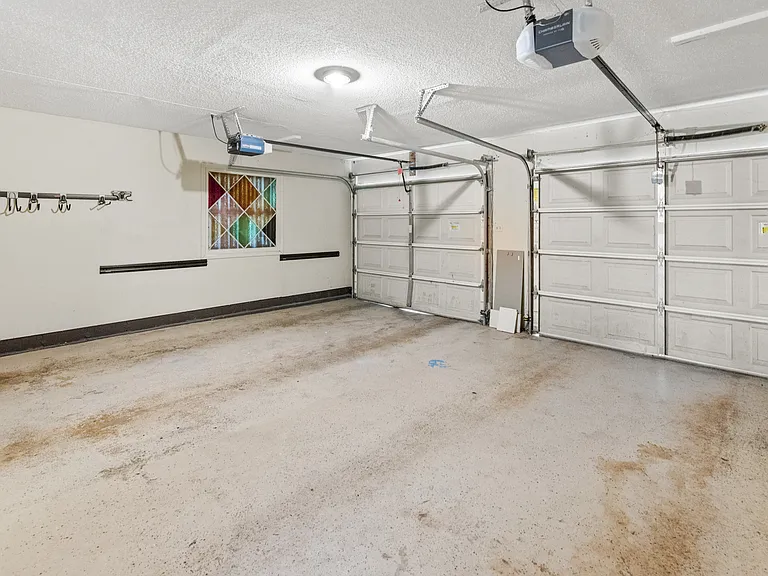 Spacious 2-car garage with automatic door openers, wall hook storage, and room for additional storage or a workshop.