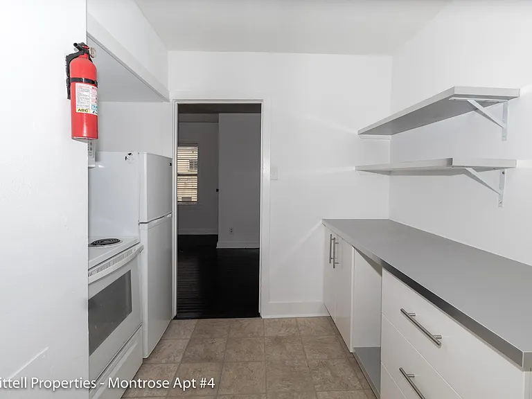 View of kitchen entrance from the kitchen sink. electric stove range and full sized refrigerator.
