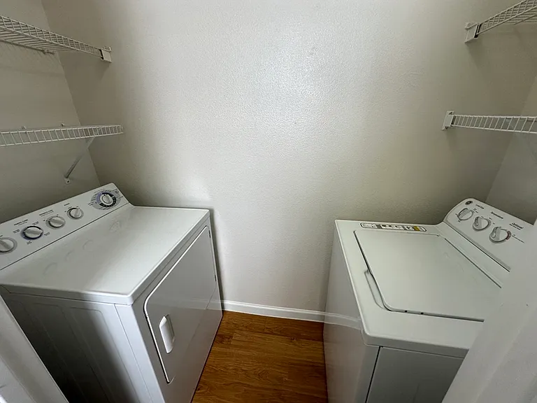 Modern laundry room with spacious washer and dryer, accented by sleek wire shelving for ample storage. Modern laundry room with spacious washer and dryer, accented by sleek wire shelving for ample storage.