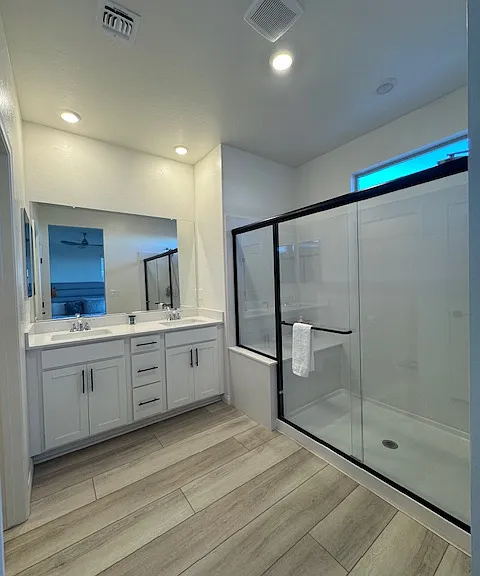 primary bathroom with dual sinks and custom built in closet