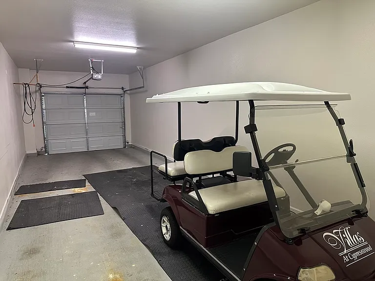 Spacious garage with a golf cart providing ample storage and convenient vehicle accommodation. Spacious garage with a golf cart providing ample storage and convenient vehicle accommodation.