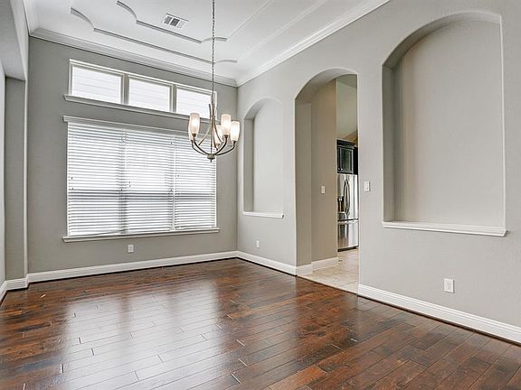 The large dining room has a triple transom windows, art niches, double tray ceiling, crown molding and hard wood floors.