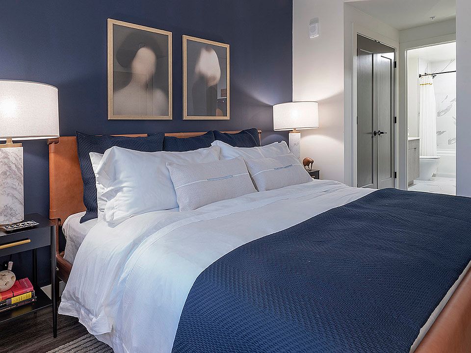 Spacious apartment bedroom with attached bathroom and wood-style flooring.