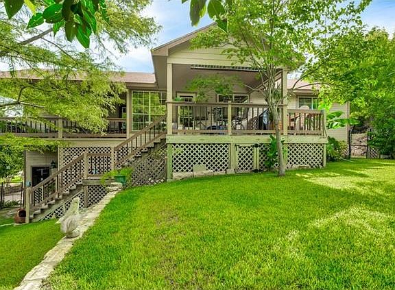 Back of the home shows the two covered decks and stairs leading to the backyard.