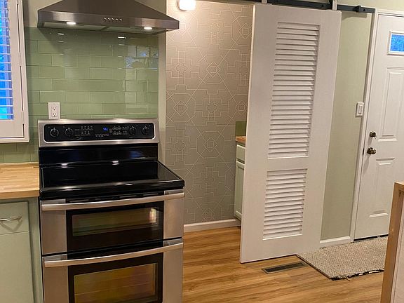 Barn-door access to double-sided pantry, vented stainless range hood, glass tile backsplash