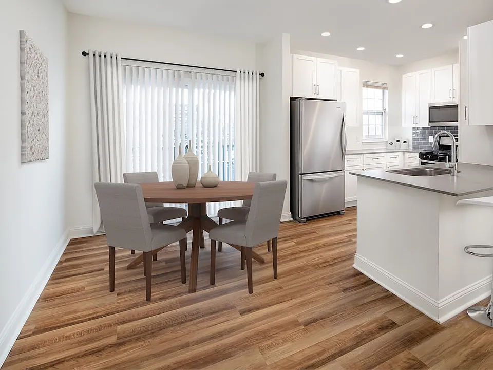 Kitchen and dining with white cabinetry, grey quartz countertops, grey tile backsplash, stainless steel appliances, and hard surface flooring