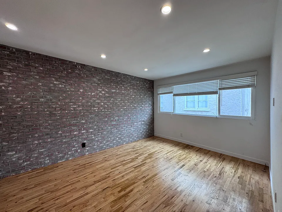 Large living room with great natural light and brick accent wall. Recessed lighting.