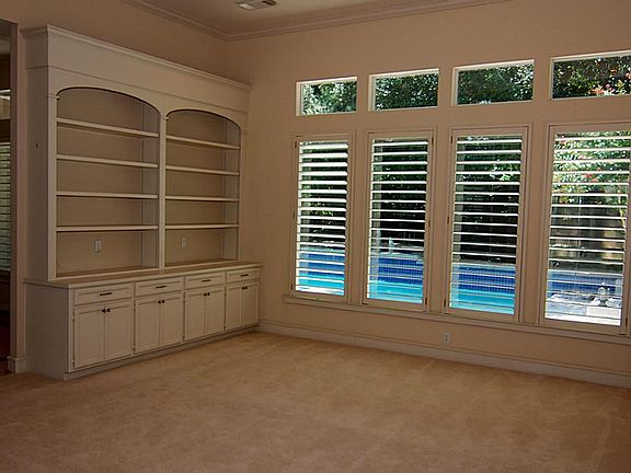 Formal living room features wall of windows, custom bookshelves and fabulous views of the pool.