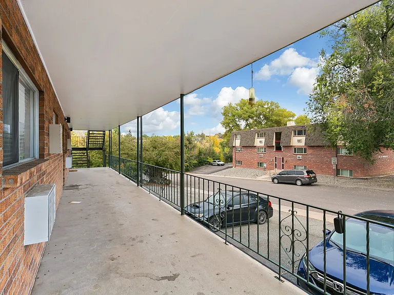 Inviting apartment balcony with scenic views of leafy neighborhood and classic brick buildings, ideal for relaxation.