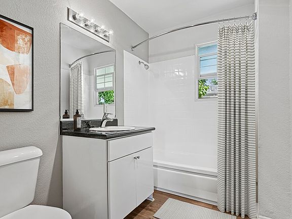 Bath with white cabinetry, black laminate countertops, and hard surface flooring