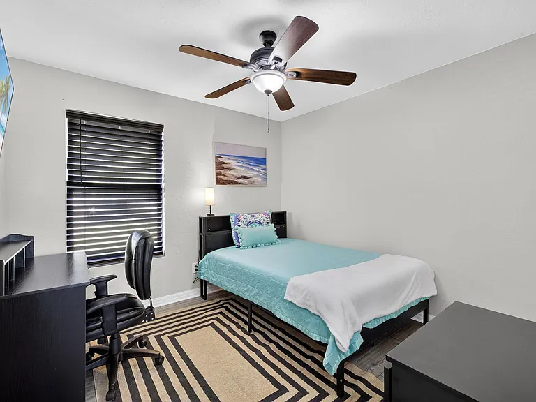 Bedroom 1 featuring a full-size bed, desk & wall-mounted television