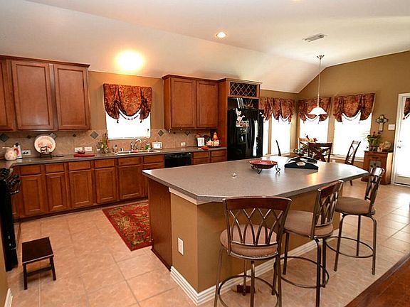 Kitchen offering tile flooring, tile back splash, Corian counter tops, built-in microwave, gas cooking, pantry and a island workspace with breakfast bar.