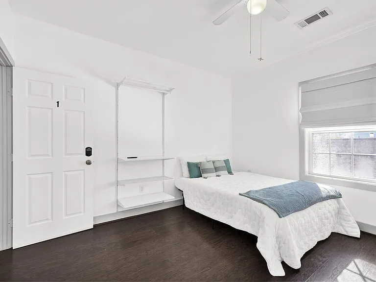 Wall mounted clothing rack is next to your queen sized bed.