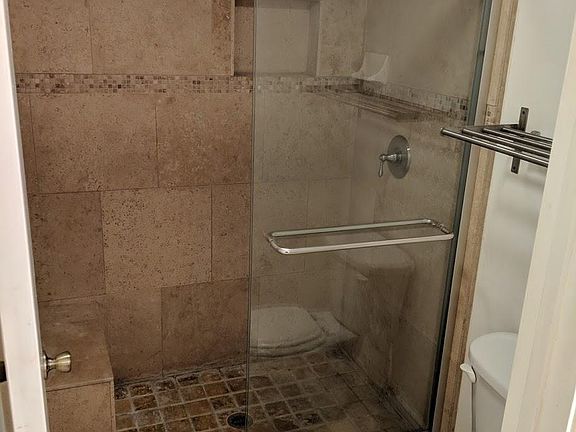 Master bathroom travertine shower with built in seat / shave stool