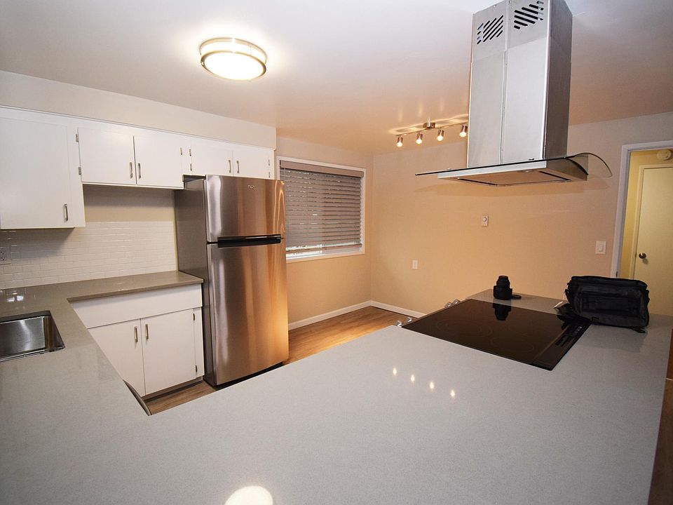 Kitchen with new quartz counter, dishwasher, range, exhaust hood, fridge, and in sink garbage disposal.