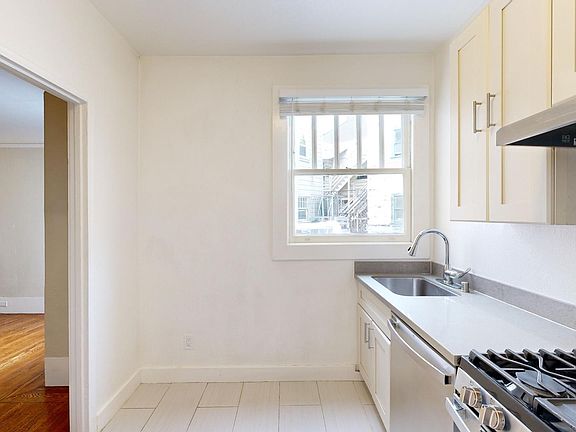 Kitchen with cabinets, stove, range hood, and sink