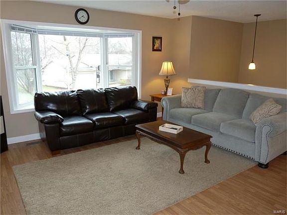 Open living room with large bay window & wood laminate flooring.