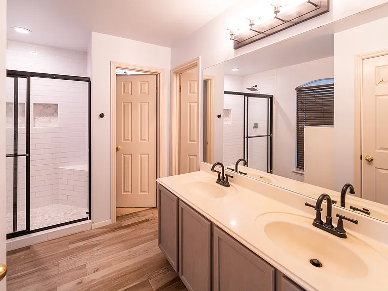 Spa-Like En-Suite Bathroom: Enjoy a large double vanity with modern fixtures, a spacious walk-in shower featuring classic subway tiling and a built-in bench, and stylish wood-look flooring.