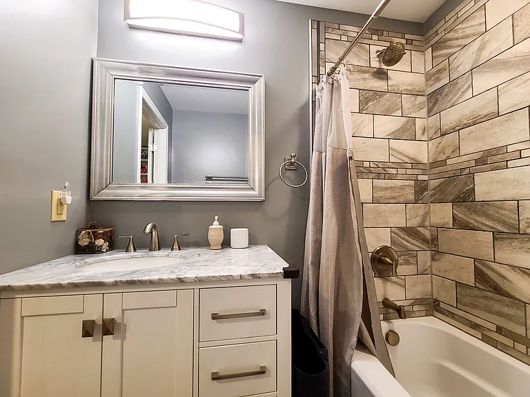 Bathroom 2/3 - Hallway bathroom with bathtub and tile in shower and tile flooring.