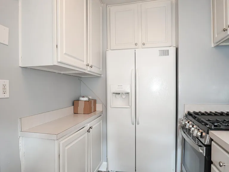Kitchen with white cabinetry, refrigerator, and gas range.