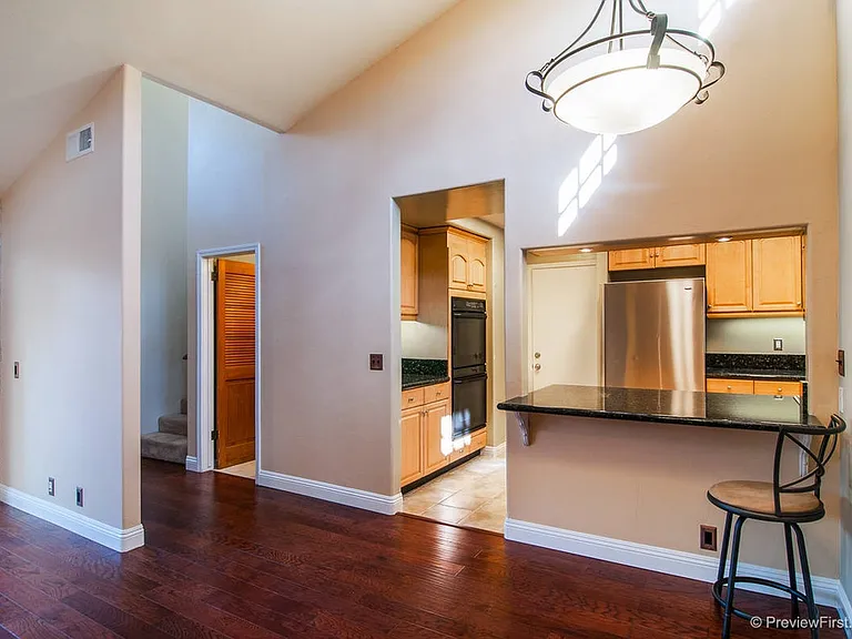 Granite countertop bar creates space for eating while sitting at bar stools. There is also a dining room table with leather chairs in the dining area.