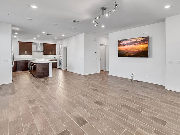 Open - concept living and dining area with modern flooring, recessed lighting, and abundant natural light.