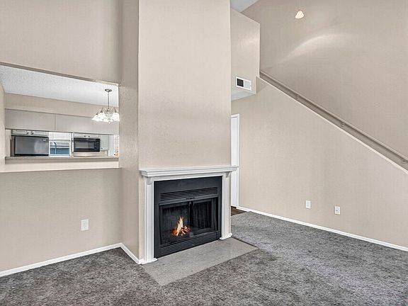 Cozy living room with plush carpeting and fireplace_ideal for modern apartment living in Grand Prairie.