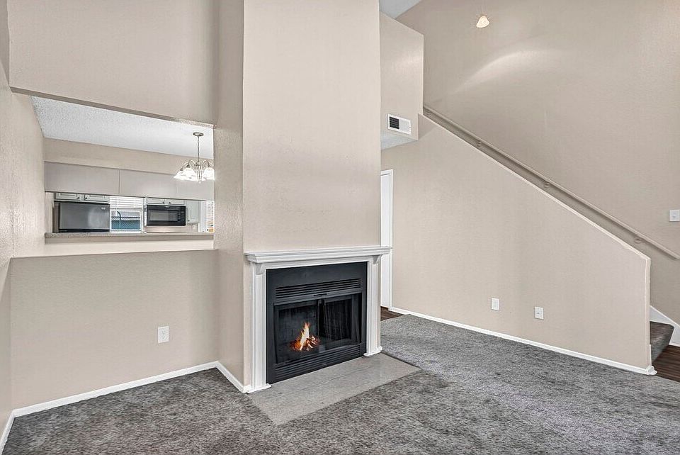 Cozy living room with plush carpeting and fireplace_ideal for modern apartment living in Grand Prairie.