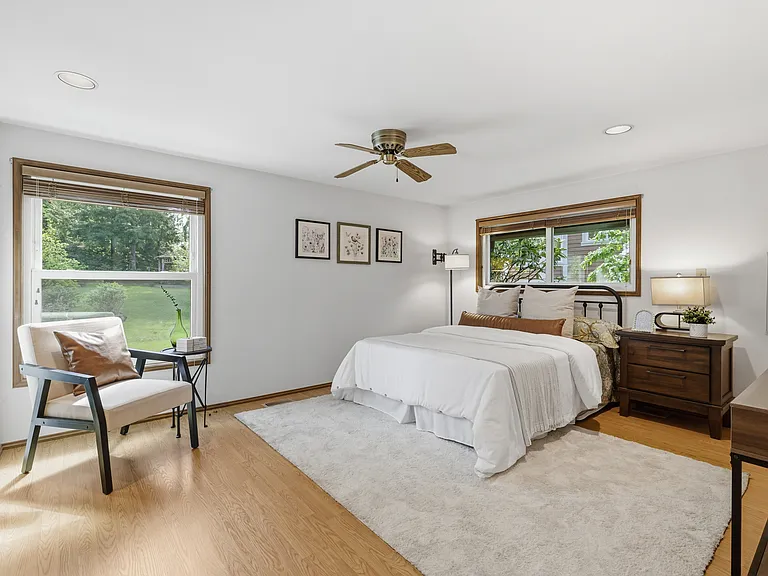 Generous primary bedroom with hardwood floors and serene yard views