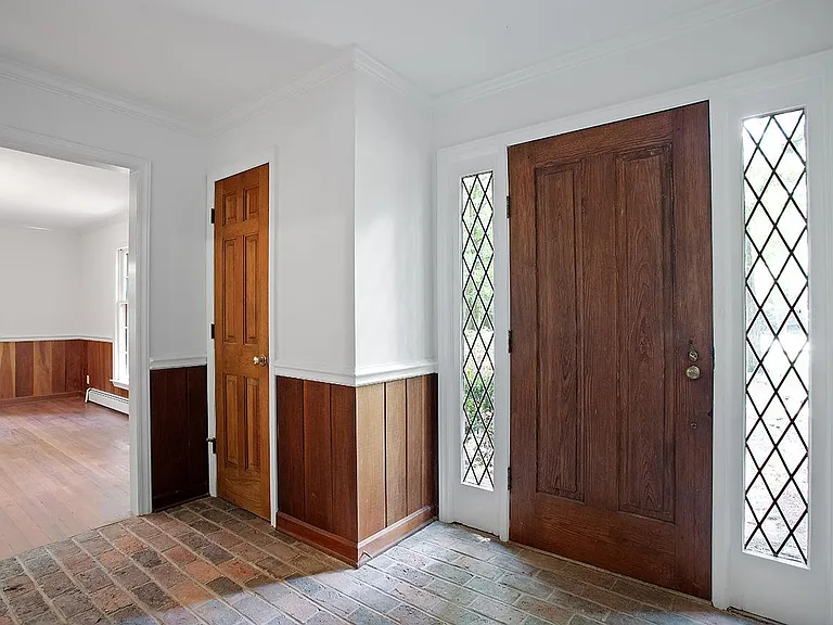 Front entrance with brick floor, hardwood door, coat closet