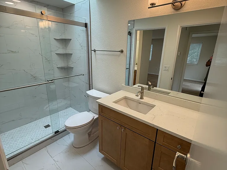 Tiled full primary bathroom with beautiful new step-in tiled shower is brightly lit under one of the skylights.