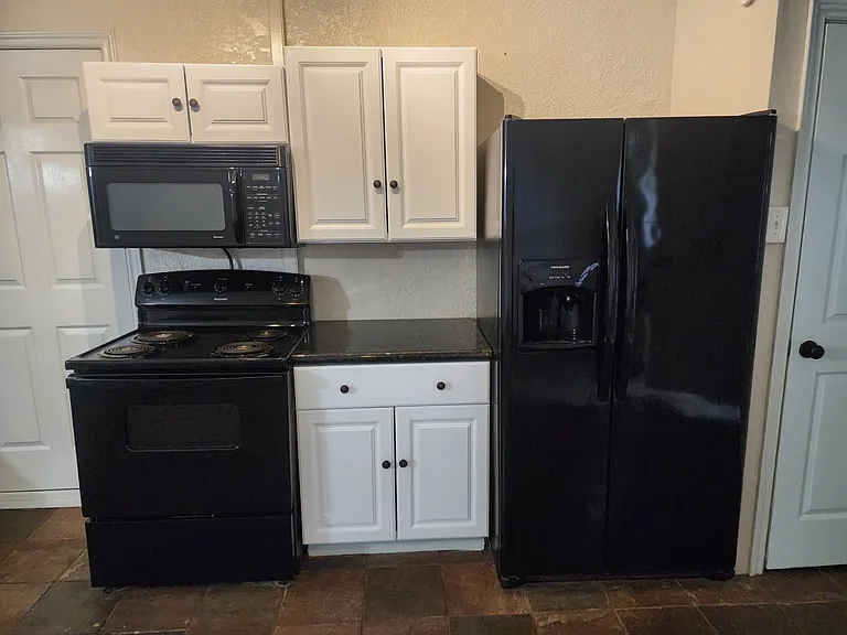 Close up of Stove, Microwave, Fridge with ice and water maker and granite countertops.