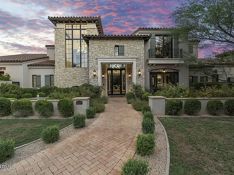 Elegant Mediterranean-style estate with striking stone facade and private, landscaped entry.
