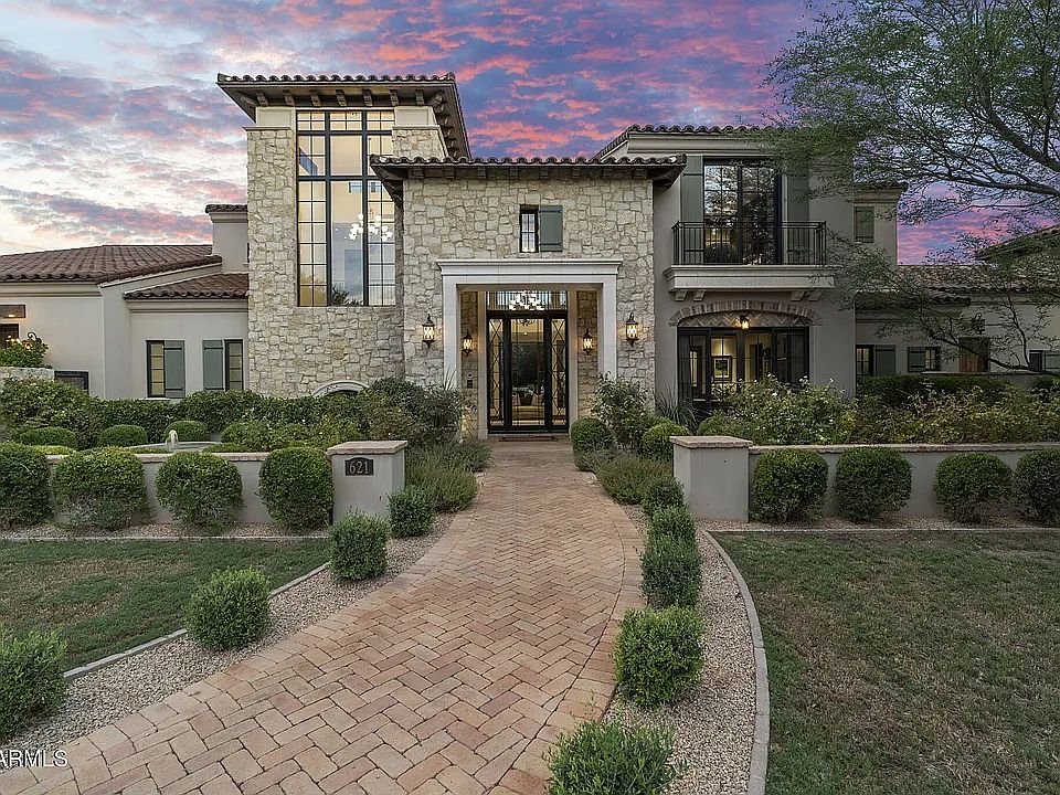 Elegant Mediterranean-style estate with striking stone facade and private, landscaped entry.